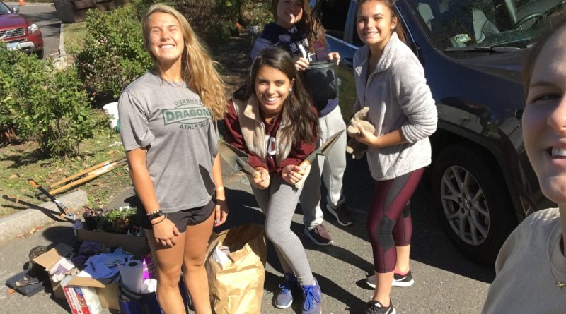 Four trinity students pose with shovels as they prepare to weed out invasive species from a local riverfront