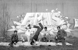 Graffiti mural promoting the Peace Train Breaking Competition, 1984-1985, Hartford, CT. Five boys and young men strike poses while breakdancing.