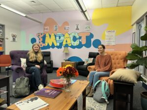two students sitting on comfortable chairs in a school community space