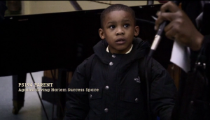 A son cluelessly watches his mother protest Harlem Success Academy's presence in their neighborhood, at a Public Space Hearing. 