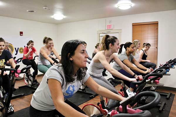 students riding exercise bikes